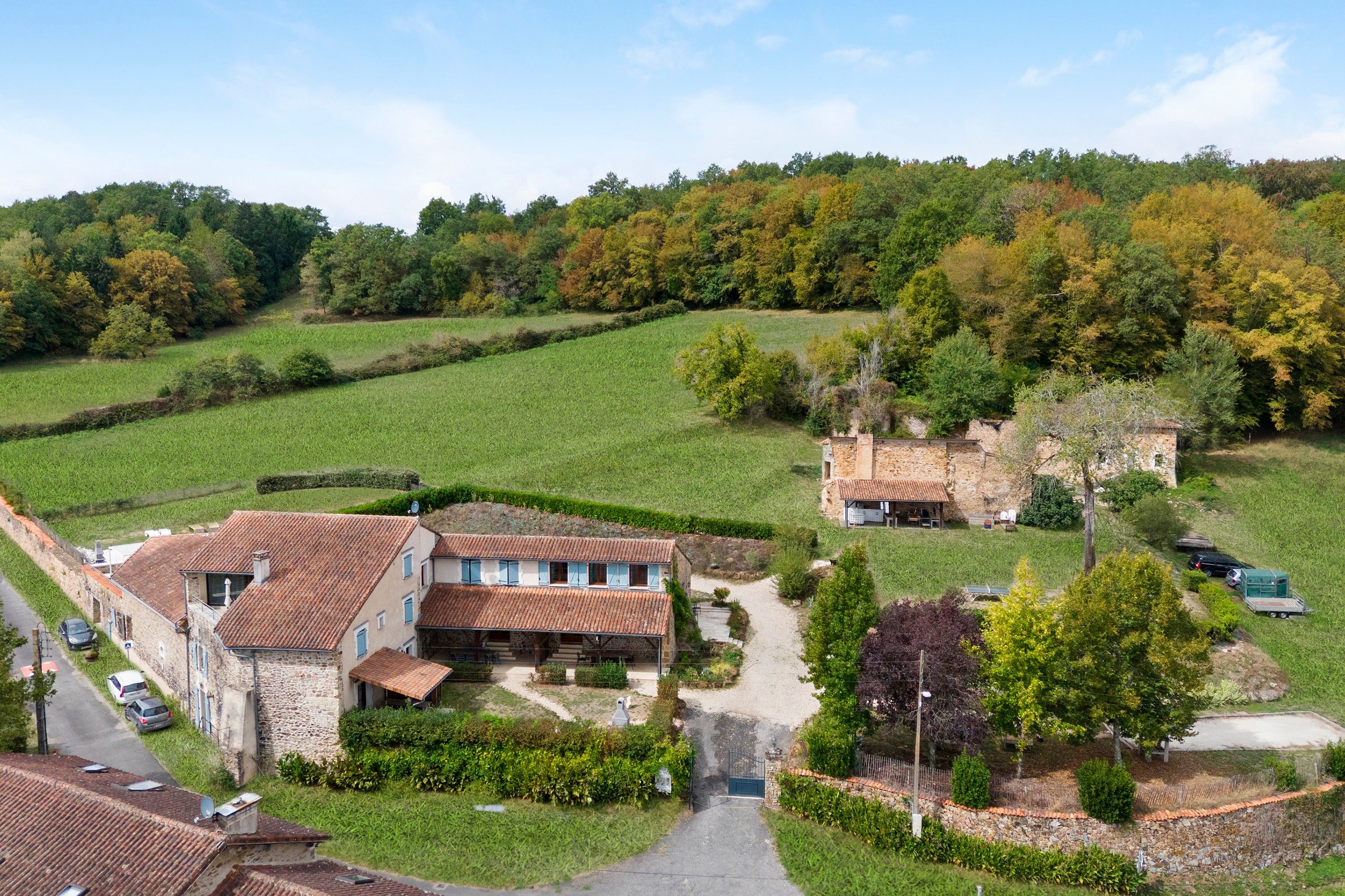 Ein ländliches Anwesen mit einem Steinhaus, einer gepflasterten Auffahrt und umliegenden Feldern.