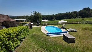 A backyard with a swimming pool, a barbecue grill, and a fenced area with outdoor seating. - Ferienhaus 'Domaine de Bellac - 32 Personen' mit privatem Pool, Terrasse und WLAN (Roussines)
