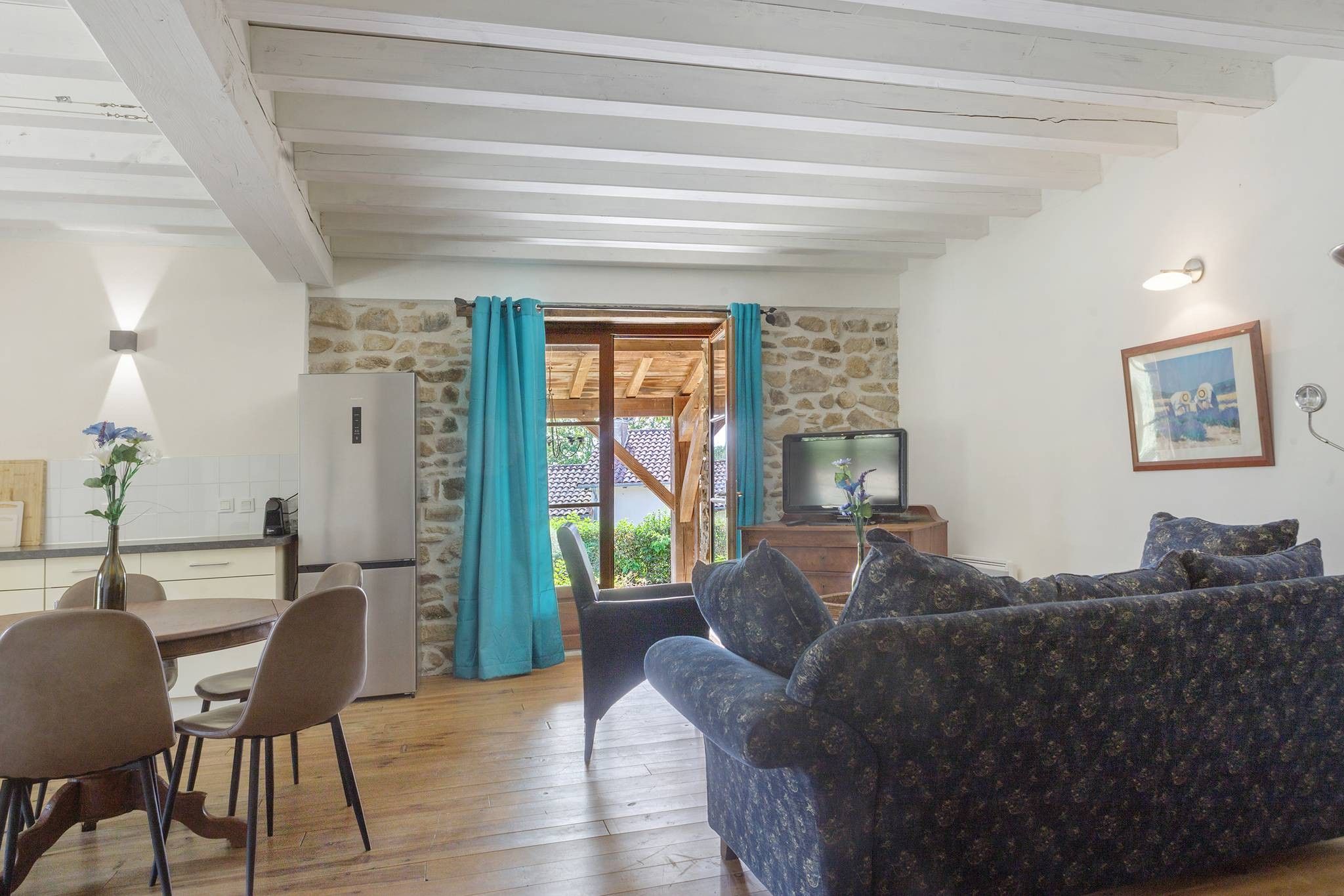 Una sala de estar con un sofá, un televisor y una pared de piedra.