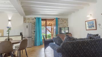 Una sala de estar con un sofá, un televisor y una pared de piedra.