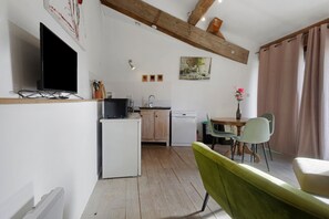 A compact kitchen with a refrigerator, a sink, and a dining area with a table and chairs.