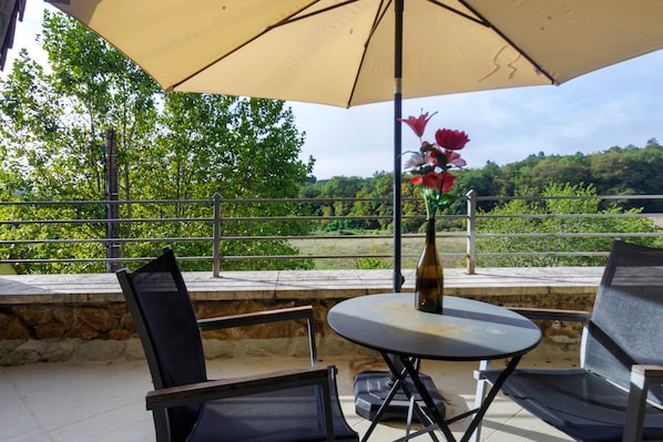 An outdoor seating area with a table, chairs, and an umbrella.
