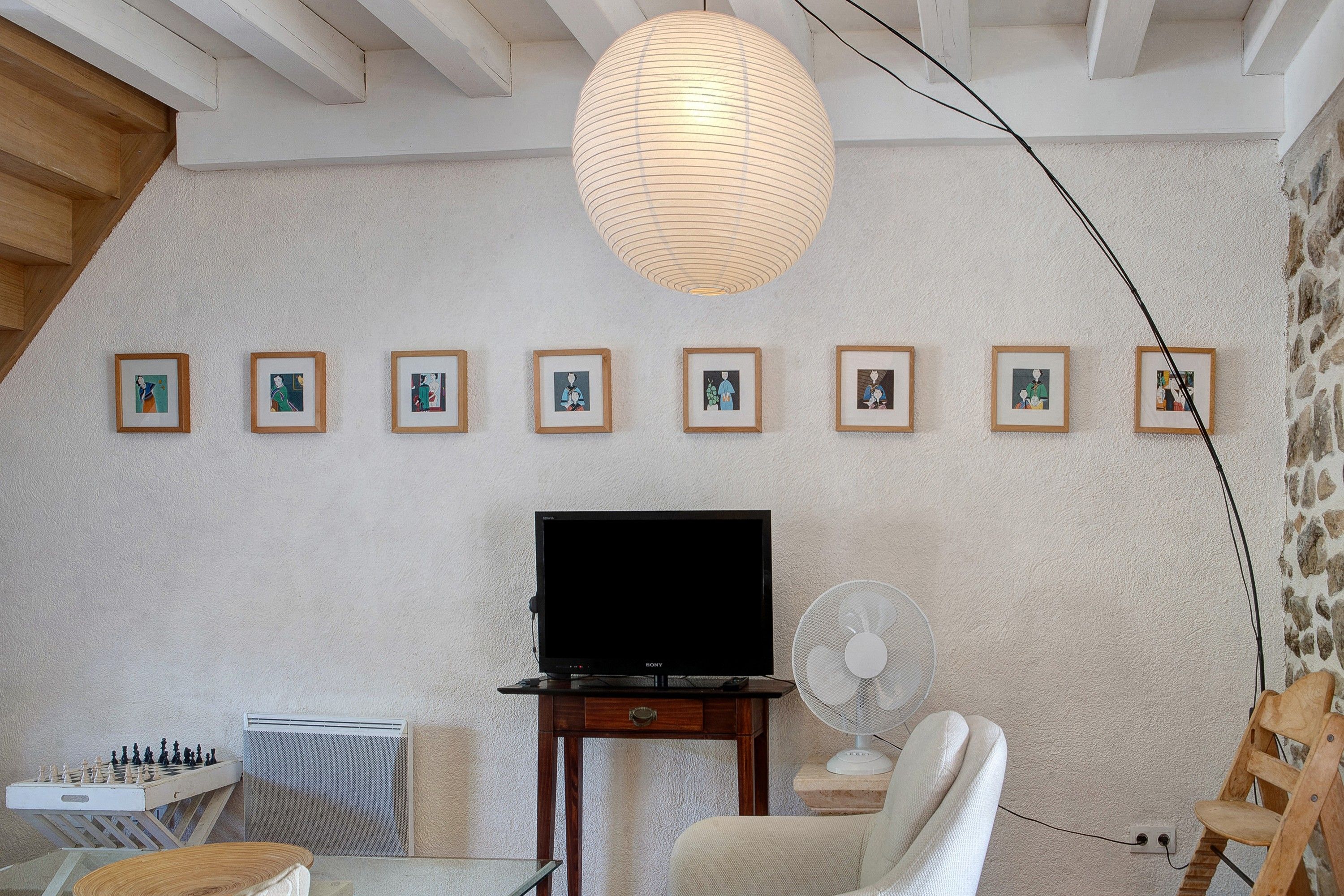 Ein Zimmer mit Fernseher, Ventilator und Schachbrett.