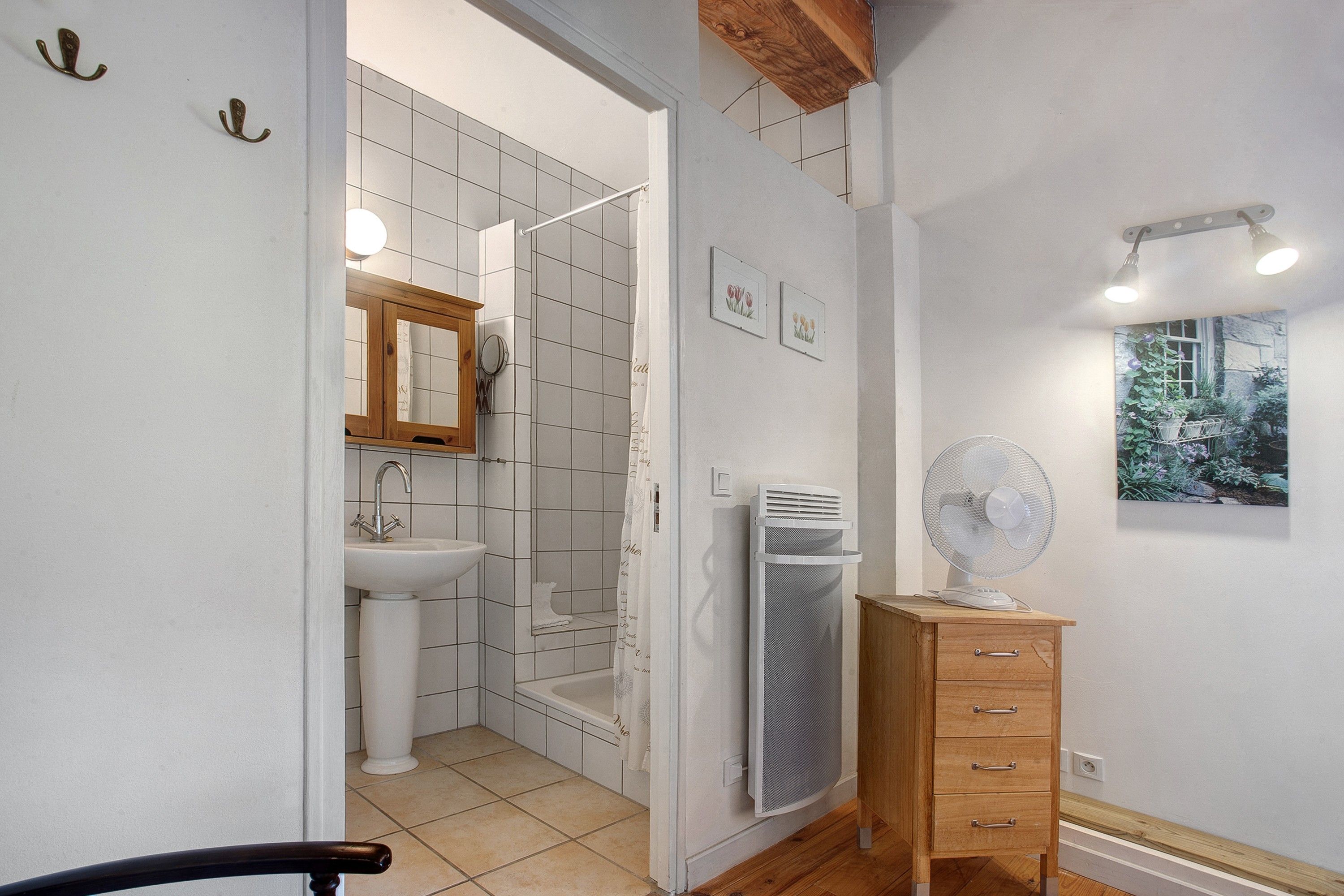 Une salle de bain avec une douche, un lavabo et un meuble en bois doté de tiroirs.