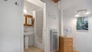 Une salle de bain avec une douche, un lavabo et un meuble en bois doté de tiroirs.