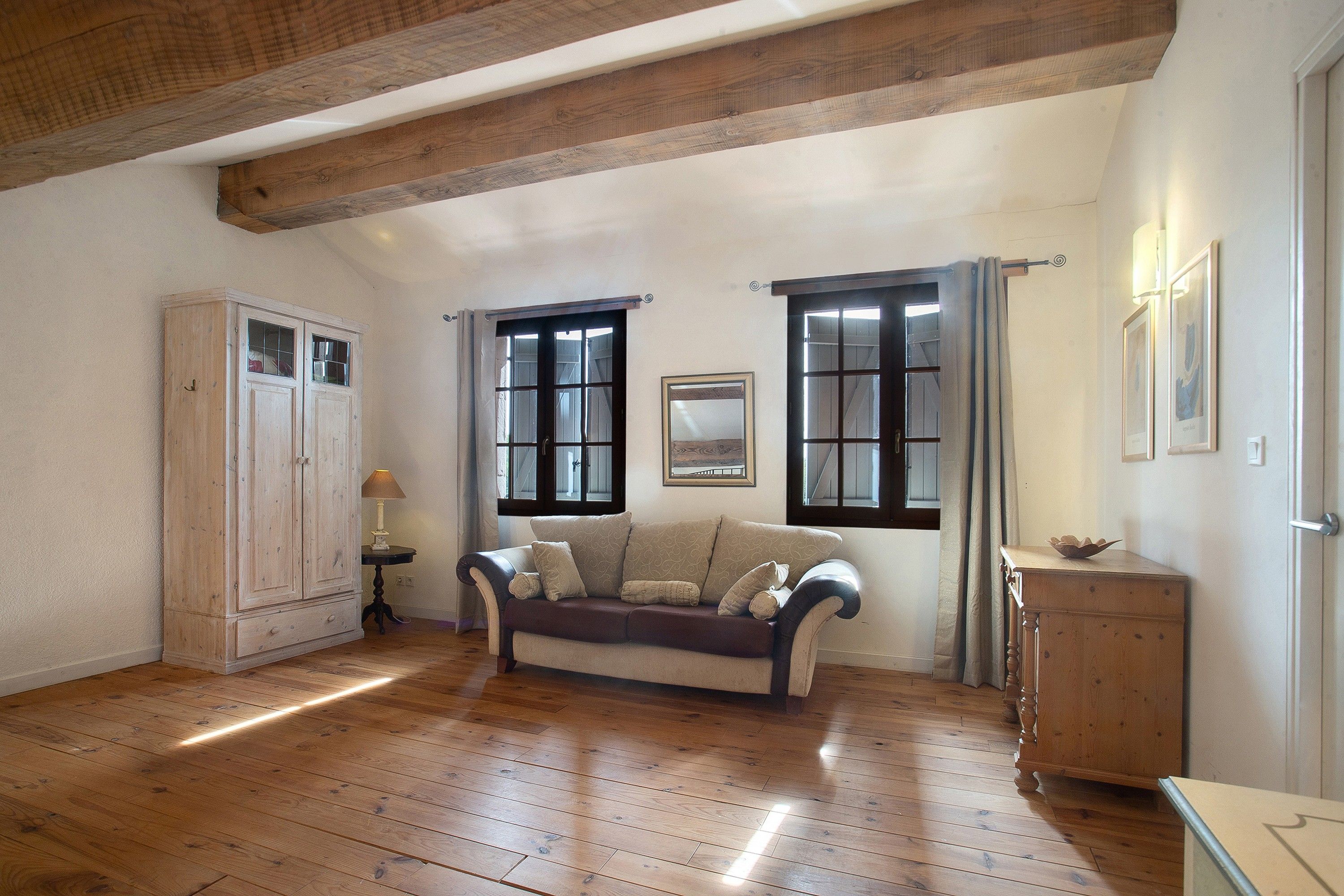 Quarto com piso de madeira, um sofá, um armário e uma porta com janelas.
