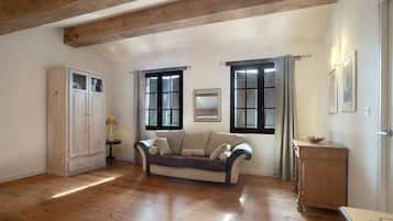 A room with wooden flooring, a sofa, a cabinet, and a door with windows.