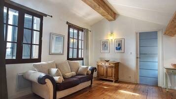 Ein Zimmer mit Holzboden, einer Couch, einem Schrank und einer Tür.