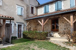Ein Gebäude aus Stein mit einer überdachten Terrasse und Sitzgelegenheiten im Freien.
