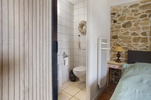 A bathroom with white tiles, a toilet, a shower, and a towel rack.