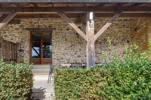 A stone building with a wooden porch, a wooden door, and a bench.