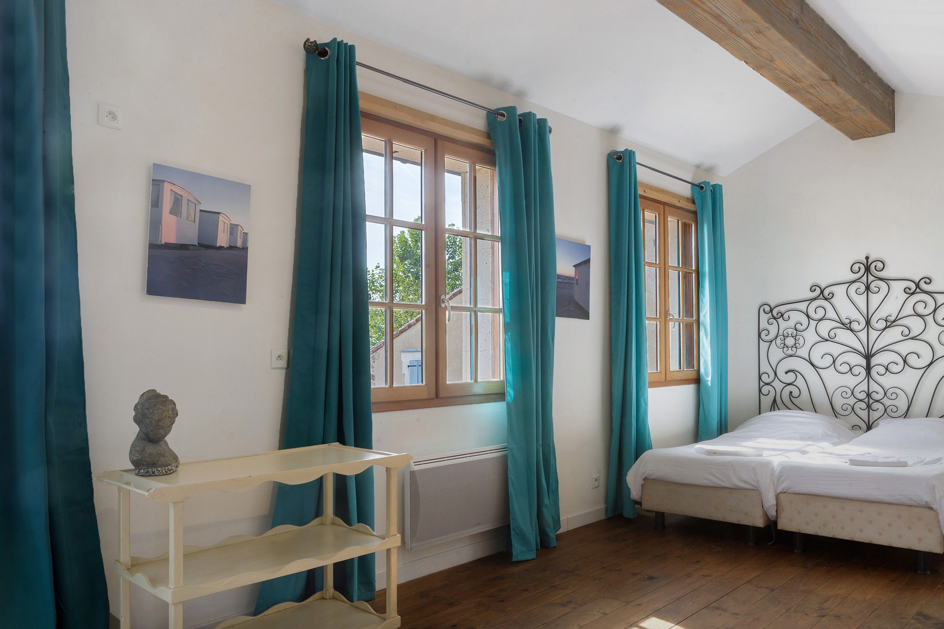 Un dormitorio con una cama, un radiador, un estante y cortinas.