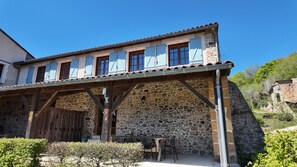 A stone building with a covered patio, wooden beams, and a table with chairs.
