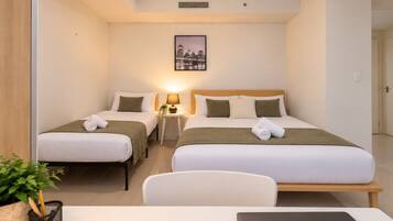 Ein Hotelzimmer mit zwei Betten, einem Schreibtisch, einem Stuhl, einer Lampe und einem gerahmten Bild an der Wand.