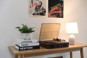 A table with a vintage radio, a lamp, and books titled 'LONDON,' 'PARIS,' and 'NEW YORK.' -  Balcony and record player minutes from Mascot (Mascot)