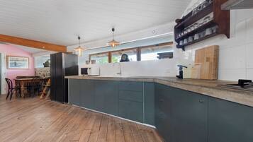 Une cuisine moderne avec un plancher en bois, un îlot central intégré doté d’un évier et une horloge au mur.