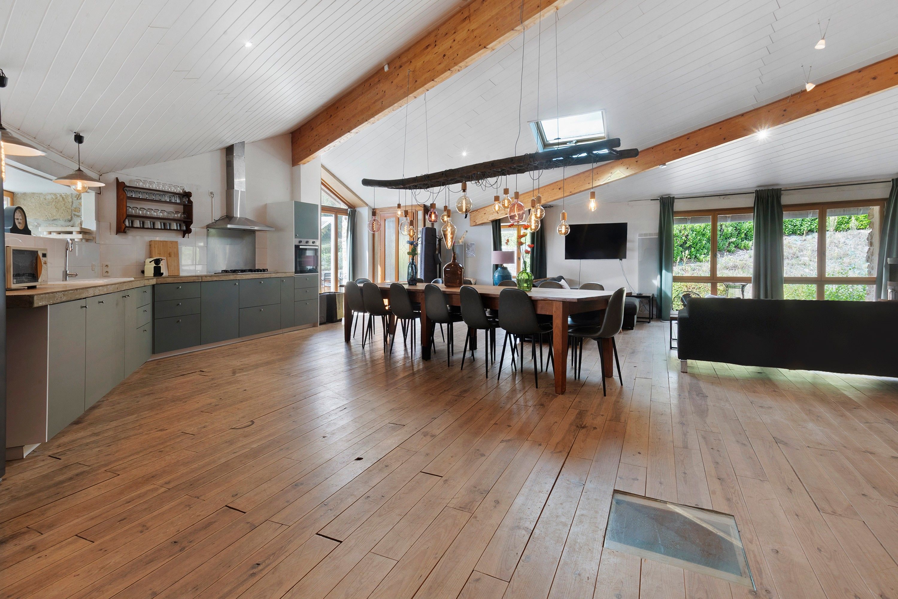 Una cocina amplia con comedor, piso de madera y un ventanal que proporciona luz natural.