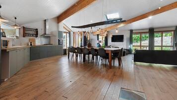 Una cocina amplia con comedor, piso de madera y un ventanal que proporciona luz natural.