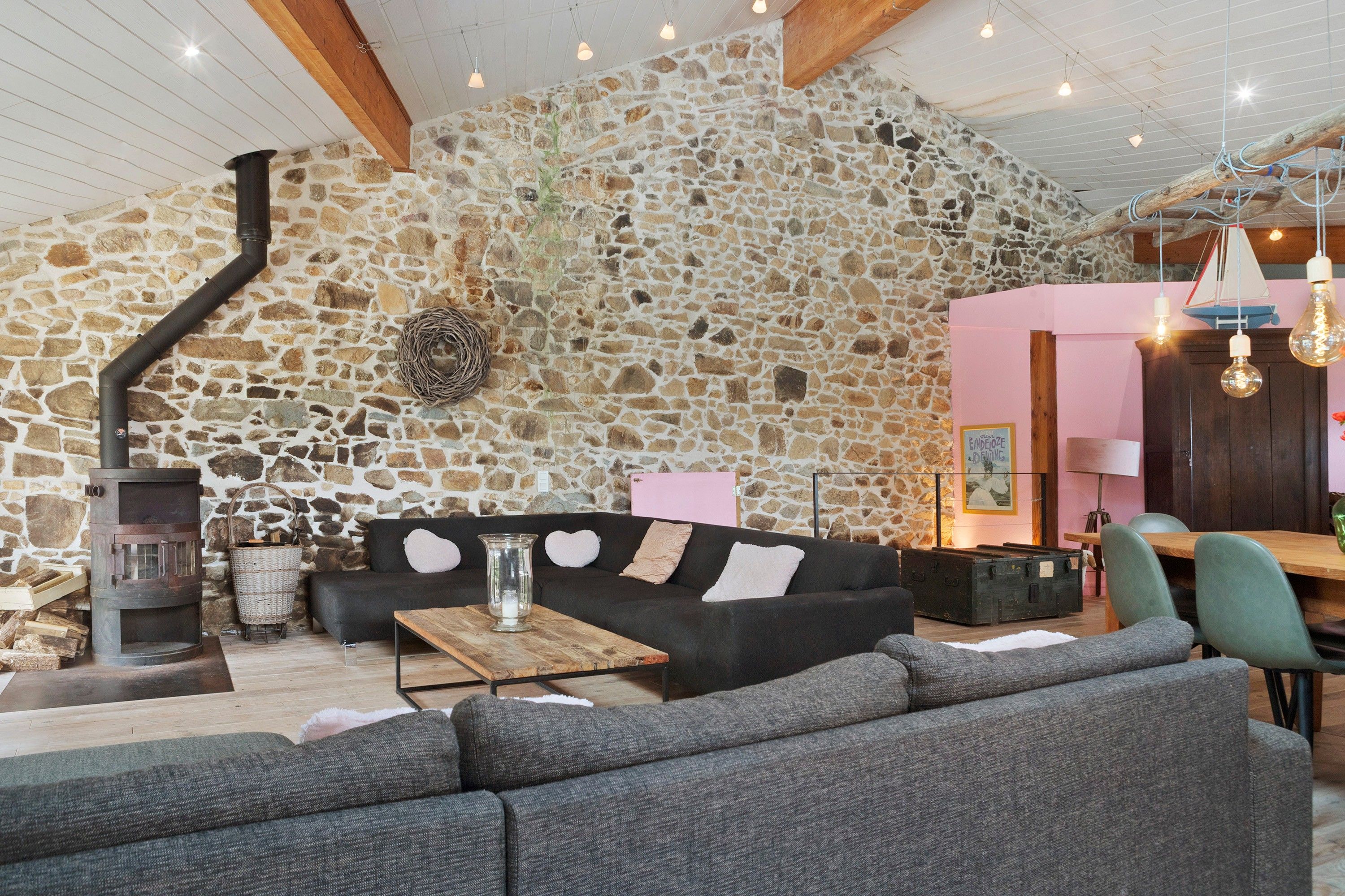 Un intérieur chaleureux avec un mur en pierre, une cheminée, un canapé et un coin repas.