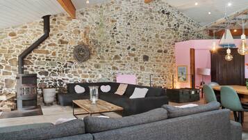Un intérieur chaleureux avec un mur en pierre, une cheminée, un canapé et un coin repas.