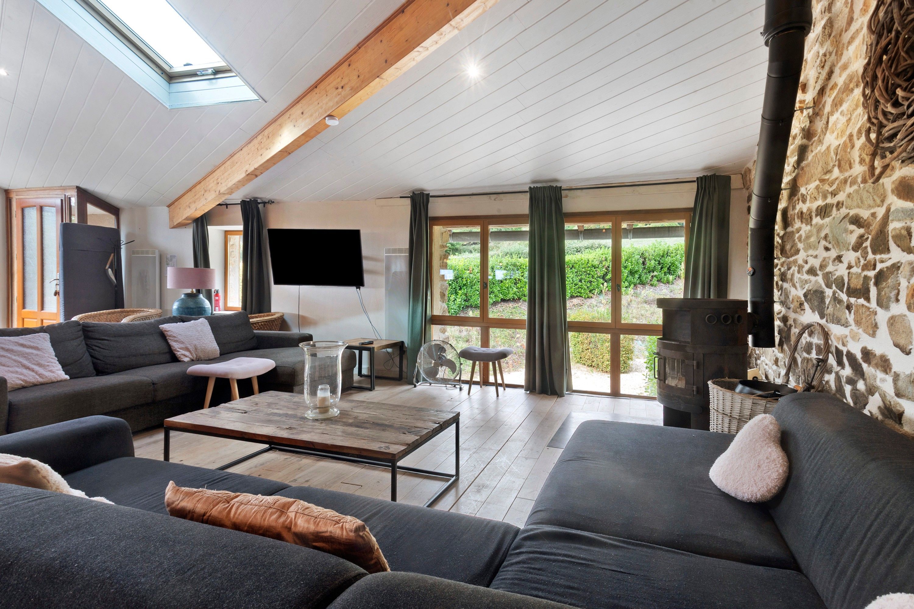 Ein modernes Wohnzimmer mit Steinwand, Kamin und großem Fenster.