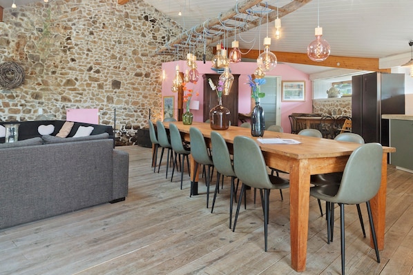 A dining area with a wooden table, chairs, and a stone wall.