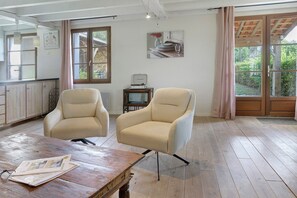 A room with two armchairs, a wooden table, and a window with curtains.
