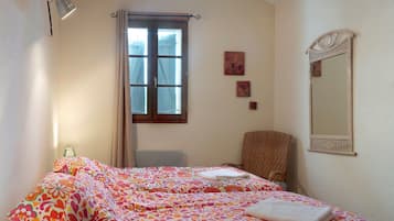 Ein Schlafzimmer mit Bett, Stuhl, Fenster und Spiegel.