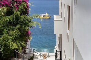 A coastal building with a balcony overlooking the sea, a boat in the distance, and lush greenery. - Apartment 'Sea View Uno 2' with Sea View, Wi-Fi and Air Conditioning (Agios Nikolaos)