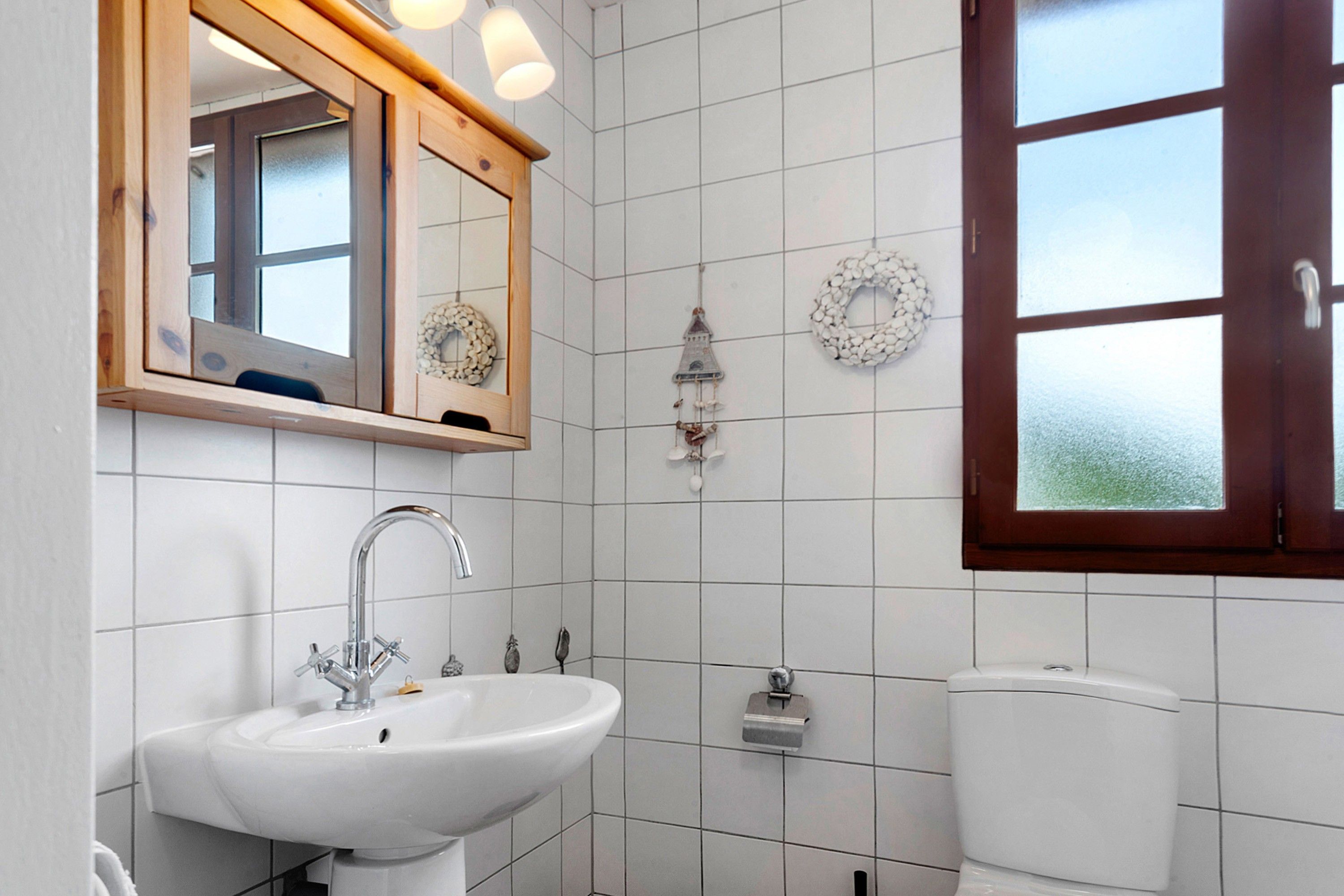 A bathroom with a white sink, a mirror with a wooden frame, and a toilet.