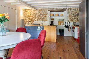 Eine moderne Küche mit Steinwand, Holzboden und Essbereich mit roten Stühlen.