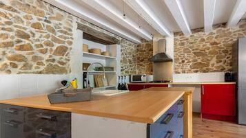Une cuisine aux murs en pierre, aux plans de travail en bois et équipée d’appareils électroménagers modernes.