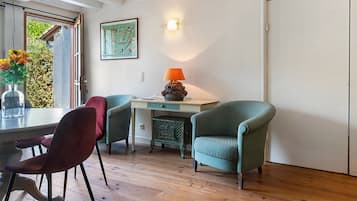 A dining area with a wooden table, two chairs, a lamp, and a framed picture on the wall.