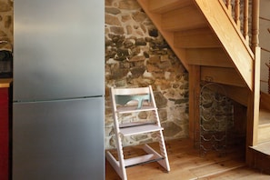 Eine Küche mit einer Steinswand, einer Holztreppe und einem weißen Regalsystem.