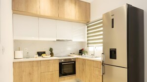 A modern kitchen with wooden cabinets, a built-in oven, a stainless steel refrigerator, and a window with blinds. - Apartment 'Sea View Uno  1' with Sea View, Wi-Fi and Air Conditioning (Agios Nikolaos)