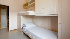 Ein Stockbett mit darüberliegendem Kleiderschrank, einem Schrank und einem Badezimmer.