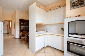 A kitchen with white cabinets, a wooden dining table, and a built-in oven.
