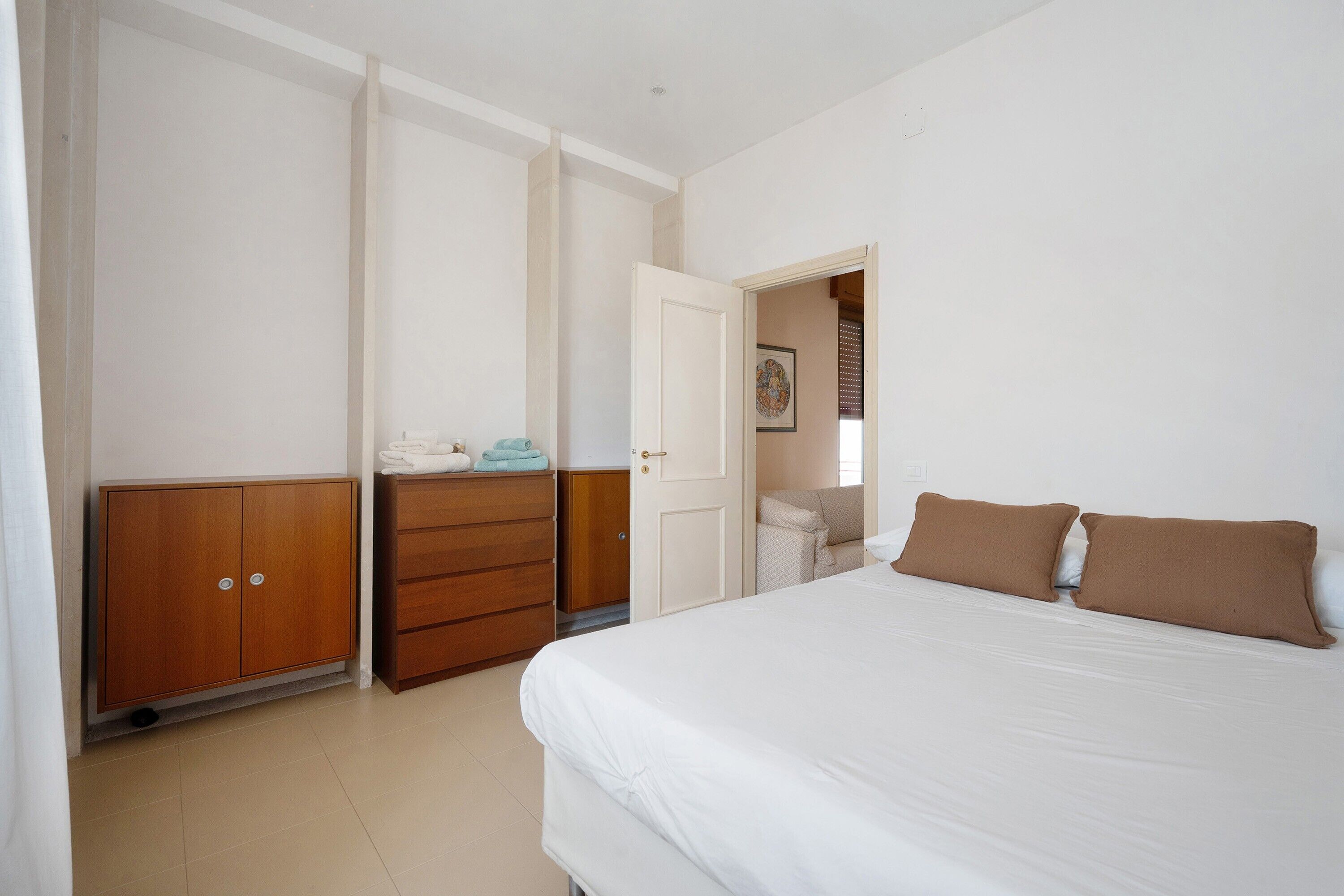 A bedroom with a bed, a wardrobe, and a door leading to another room.