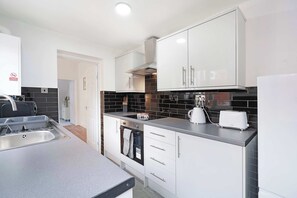 Eine moderne Küche mit weißen Schränken, einer schwarzen Küchenzeile und einem Einbauofen sowie einem Toaster.