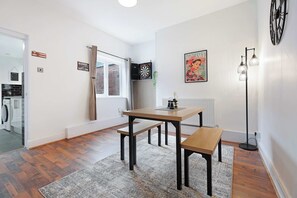 Ein modernes Wohnzimmer mit Holztisch, Bank und Dartscheibe.