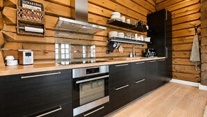 Una cocina moderna con paredes de madera, una campana extractora de acero inoxidable y un horno empotrado.