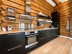 Une cuisine moderne avec des murs en bois, une hotte en acier inoxydable et un four encastré.