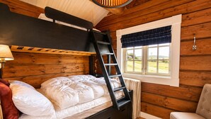 Una cama individual superpuesta con escalera, una ventana con vistas, una silla y una lámpara.
