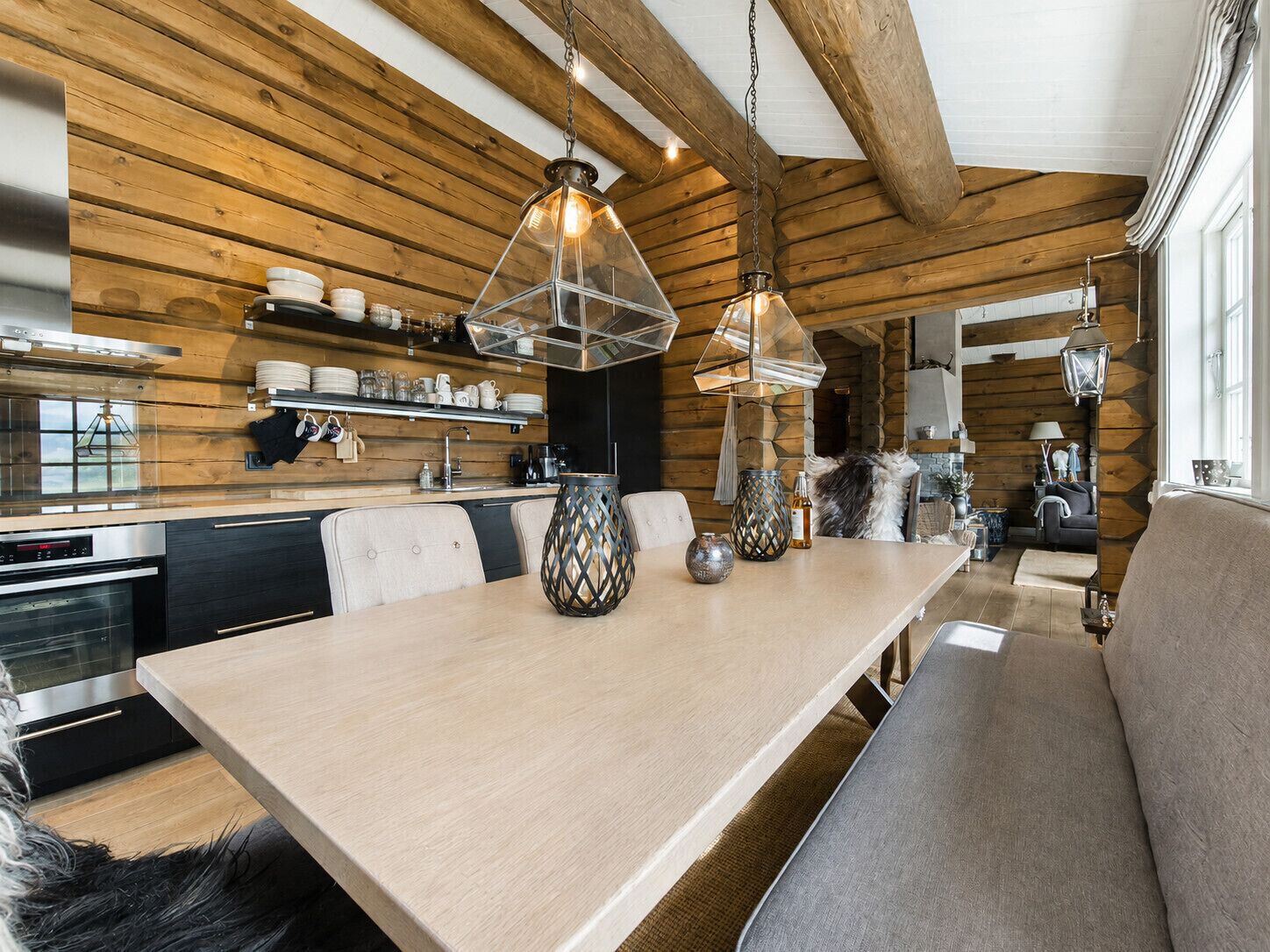 Una cucina moderna con travi in legno, un'area pranzo con una panca e illuminazione a sospensione.