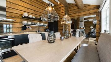 Una cucina moderna con travi in legno, un'area pranzo con una panca e illuminazione a sospensione.