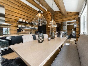 A modern kitchen with wooden beams, a dining area with a bench, and pendant lighting.