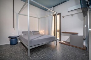 Un dormitorio moderno con cama con dosel, una mesita de noche pequeña y un banco empotrado.