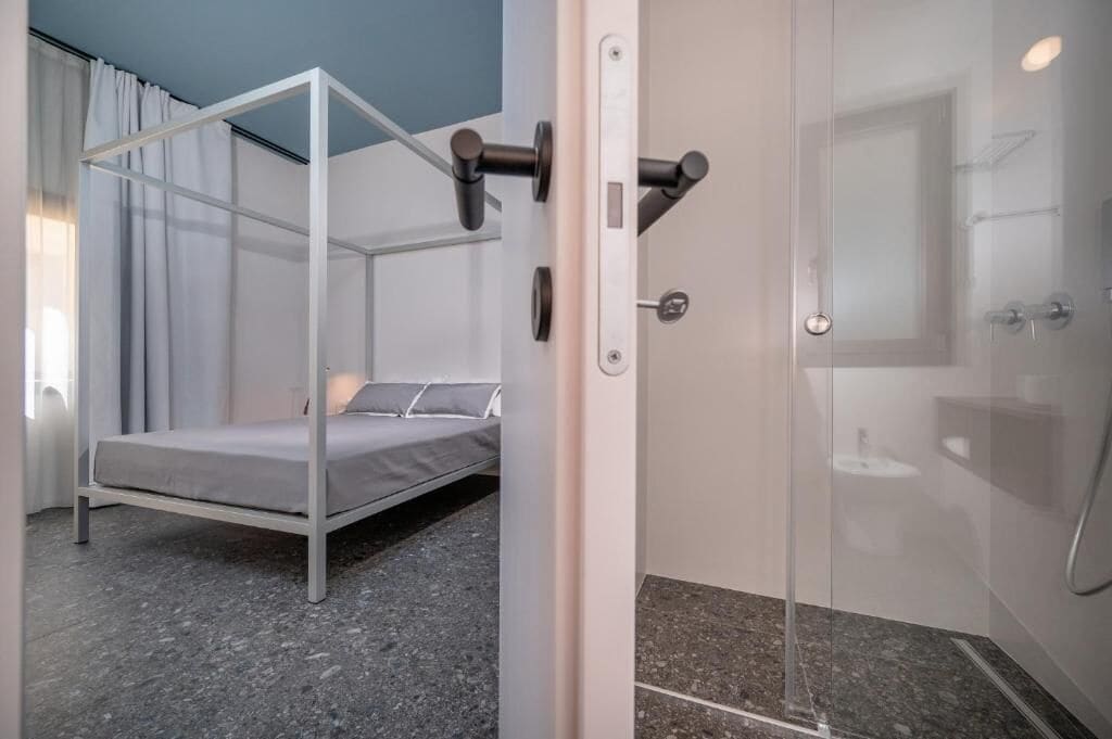 Ein modernes Zimmer mit Bett, Dusche und Glastür.