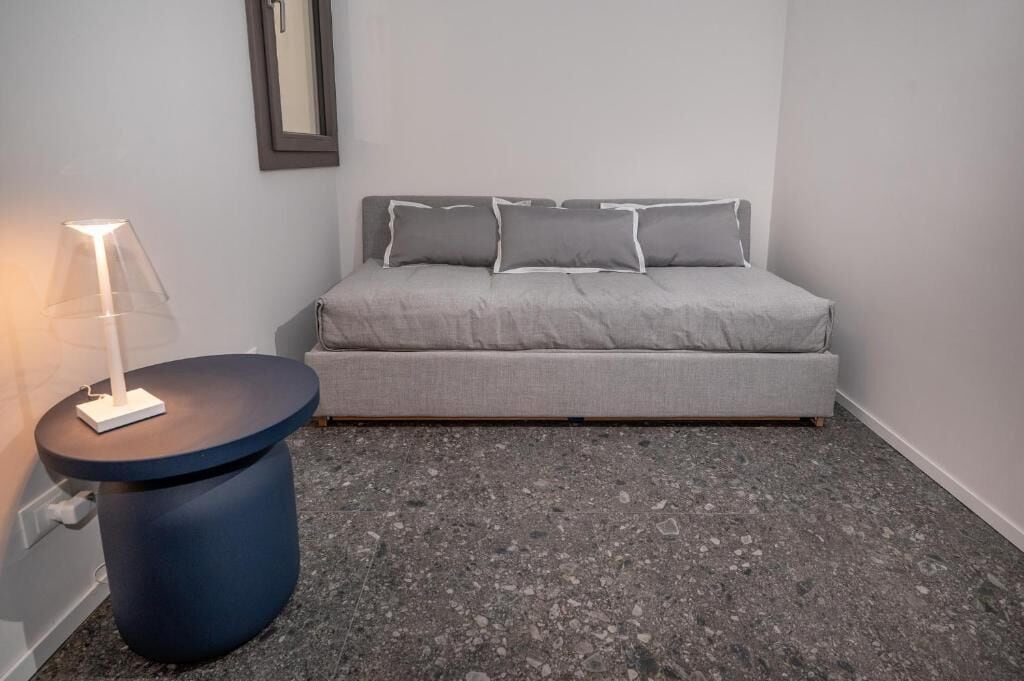 A bedroom with a bed, a round table, and a lamp.