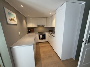 A compact kitchen with white cabinets, a built-in oven, and a microwave. - Modern apartment Møhlenpris with seaview (Bergen)